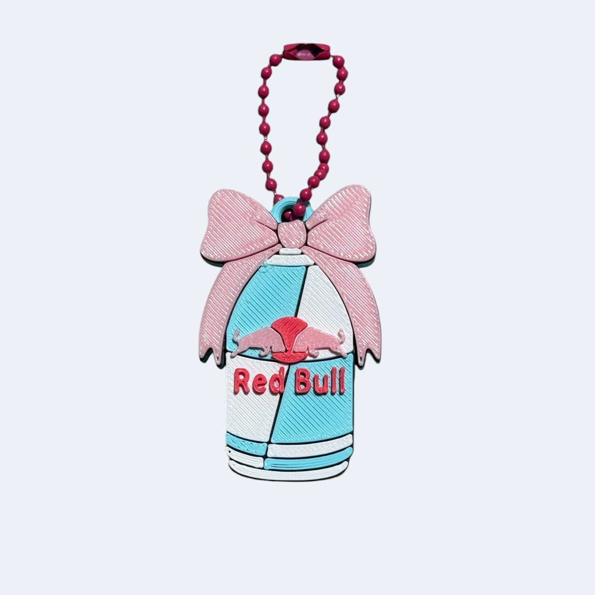 Red Bull keychain with a pink bow on a light blue background